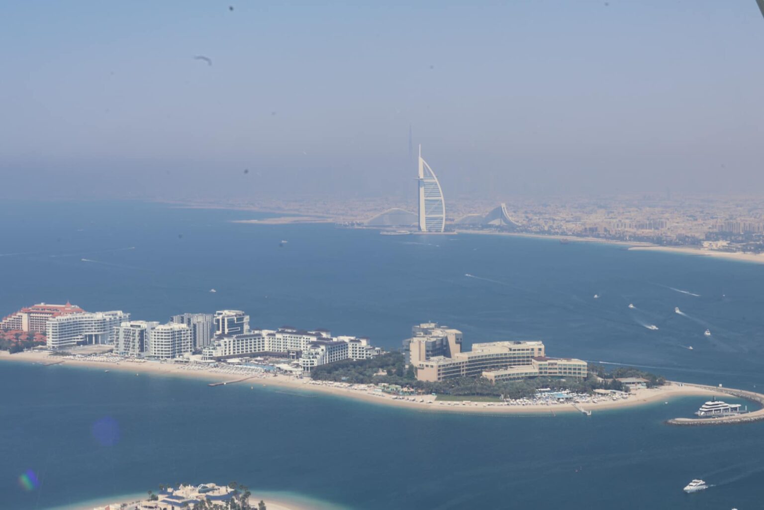A panoramic 360-degree view of Dubai’s Palm Jumeirah from The View at the Palm Tower. The iconic palm-shaped island is clearly visible, surrounded by the turquoise waters of the Arabian Gulf, with luxury villas on the fronds and resorts on the crescent.